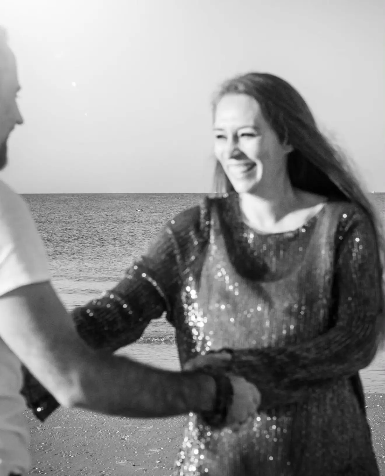 Séance couple en noir et blanc : leurs mains réunies, et le sourire qu'ils échangent au même moment.
