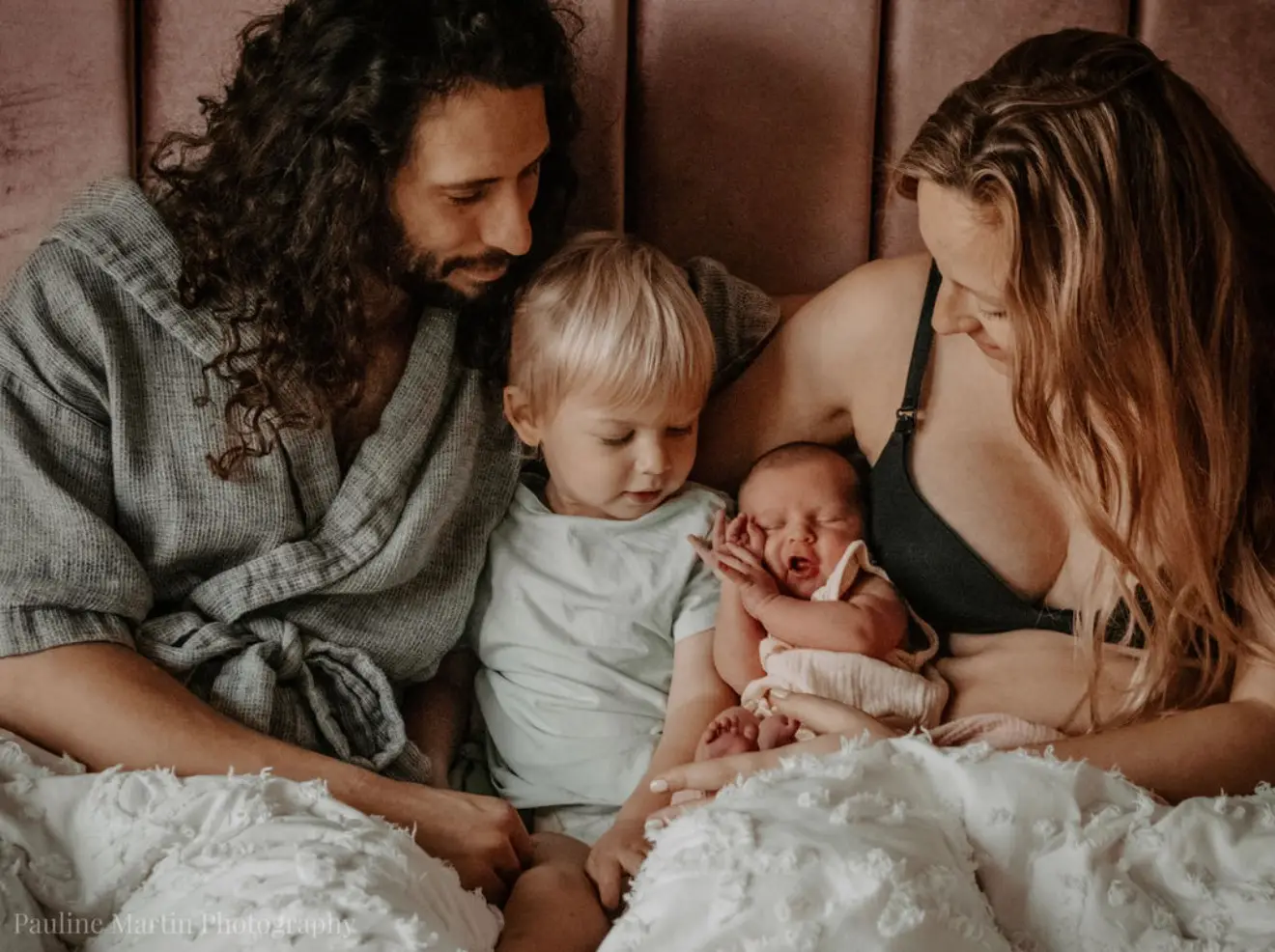 Séance naissance à domicile : la famille réunie dans le lit au réveil, le nouveau-né au centre.
