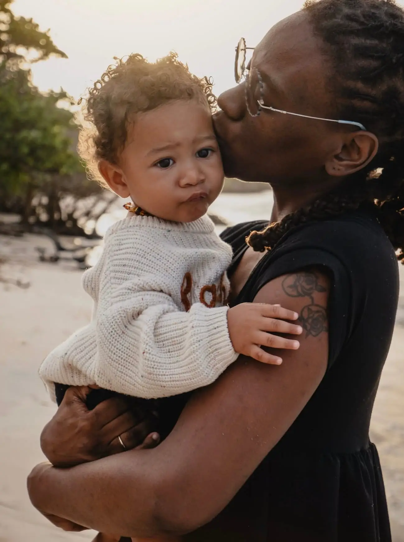 Séance famille sur la plage de Bois Jolan : une maman embrasse son bébé qu'elle porte contre elle, en fin de journée.